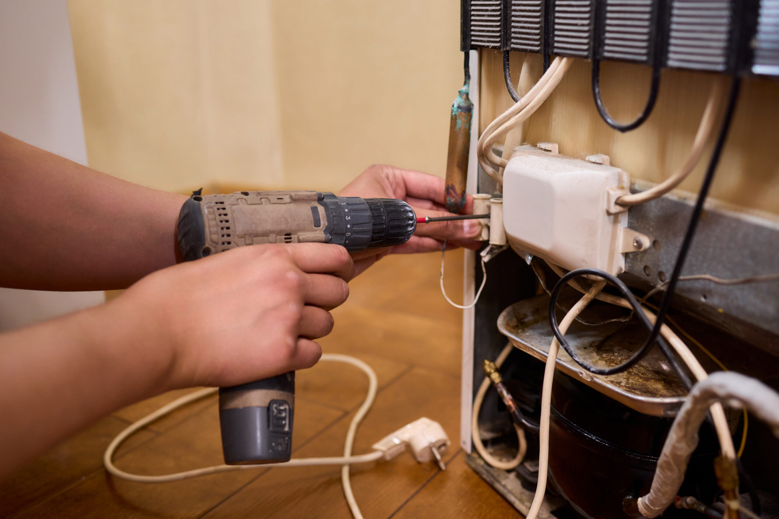 photo-hero-15 fixing appliances using a power drill inside a refrigerator for repair and maintenance tasks