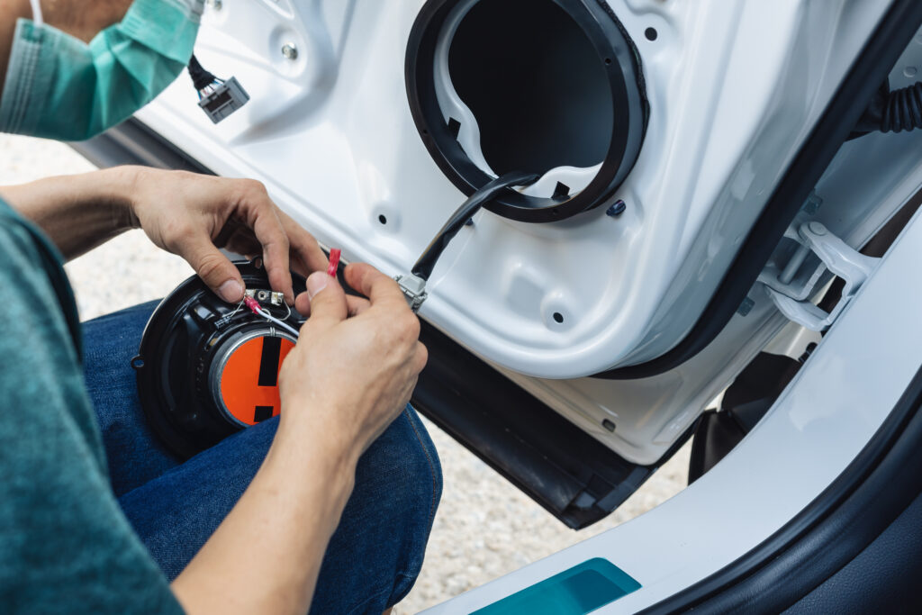 services-2 mechanic man installing speaker on vehicle door part in garage